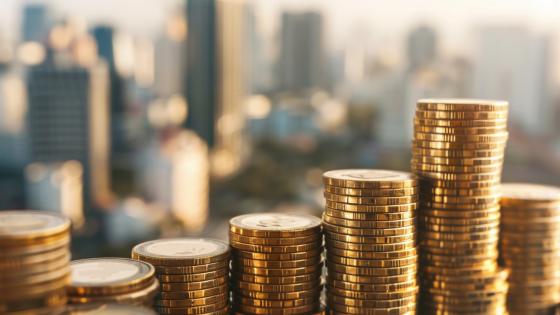 Piles of coins with tall buildings in background