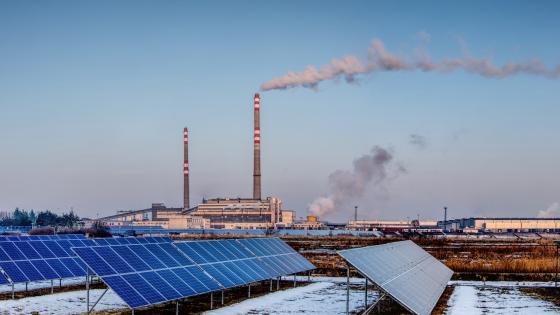 Solar panels with coal power plant in background