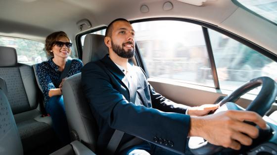 Taxi driver driving a car with businesswoman