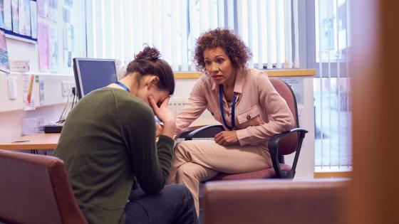 Female College Student Meeting With Campus Counselor Discussing Mental Health Issue