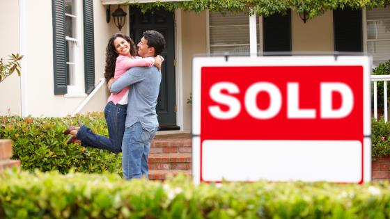 couple outside home with sold sign