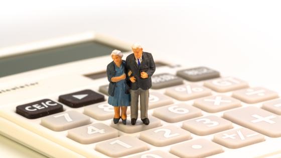 Model of elderly couple standing on calculator