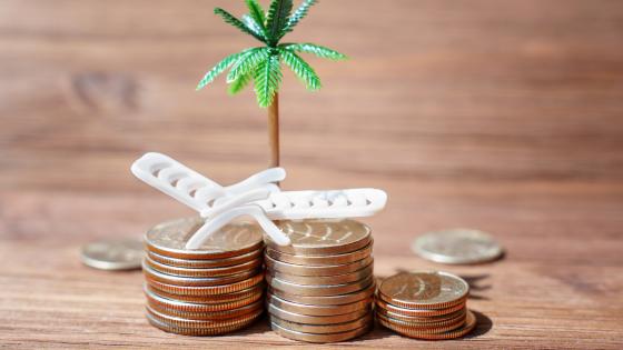 Toy deck chair and palm tree on piles of coins