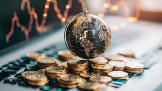 Globe, stacks of coins and financial chart on laptop